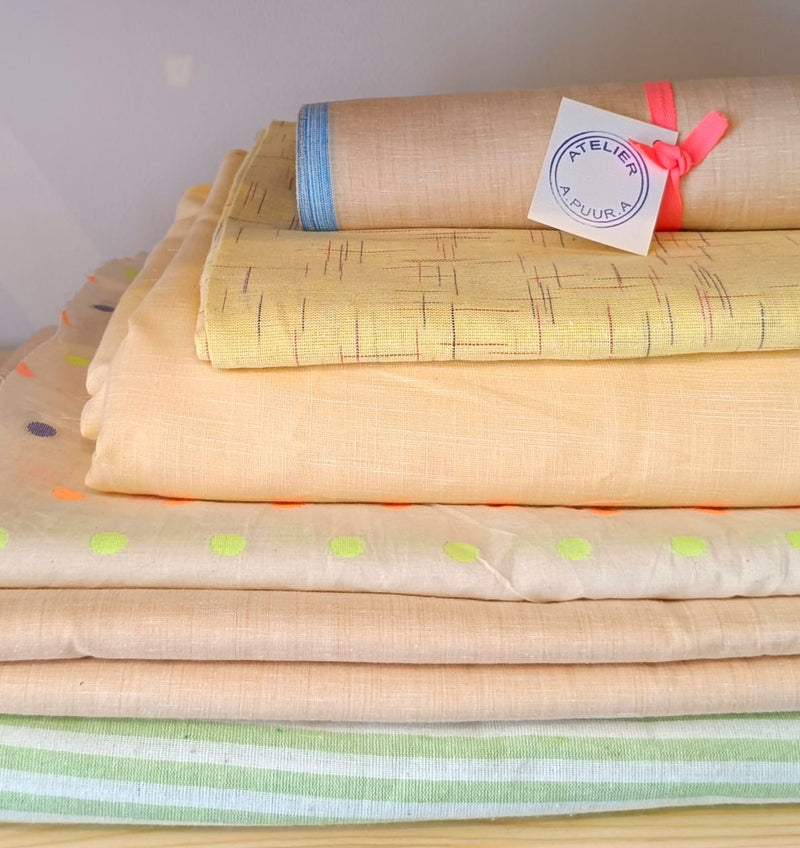 A stack of yellow fabrics with different patterns displayed in the ATELIER A.PUUR.A shop in Antwerp 
