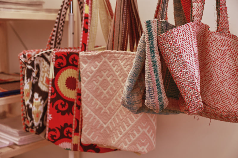 A selection of different handbags hanging from a bar on display in ATELIER A.PUUR.A showroom 