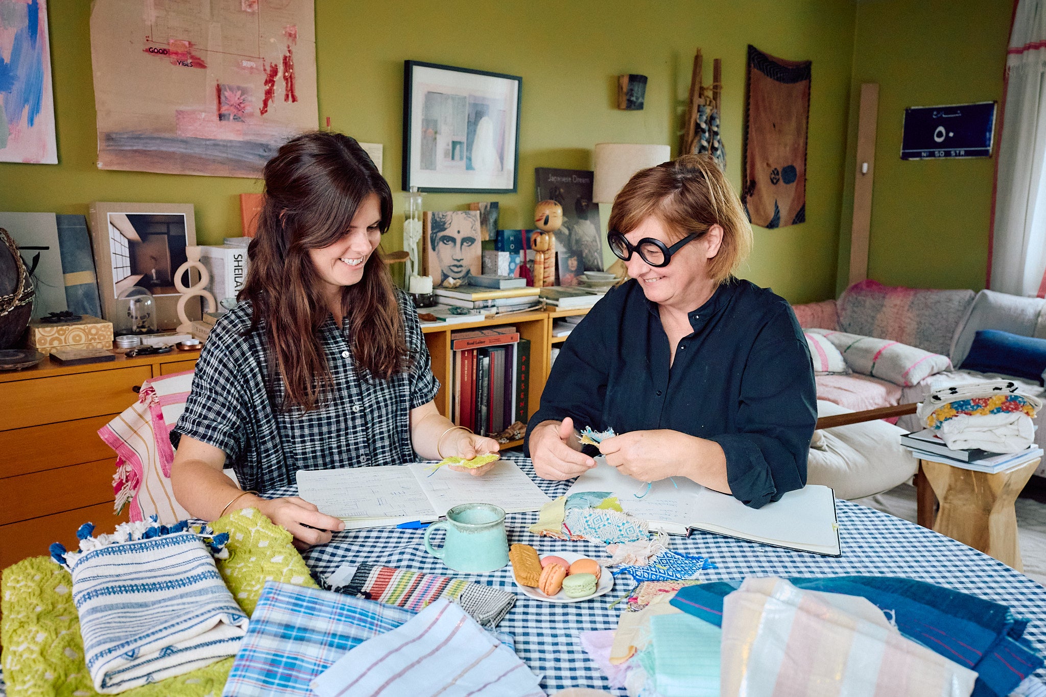 Founders Valerie Tjantele and Katrien Buyle of ATELIER A.PUUR.A sitting at a table discussing textile swatches 